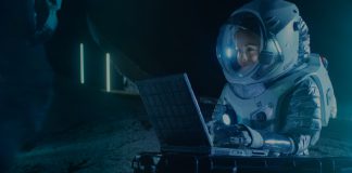 Female Astronaut Wearing Space Suit Works on a Laptop, Exploring Newly Discovered Planet, Communicating with the Earth. In the Background Her Crew Member and Space Habitat. Colonization Concept.; Shutterstock ID 1042736182; Cliente/Job: -; CNPJ a Faturar: -; Vencimento da NF / ObservaÃ§Ãµes: -