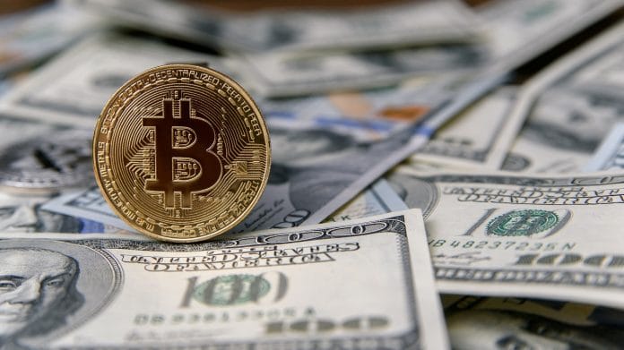 Moeda digital Bitcoin em cima de pilha de dólares