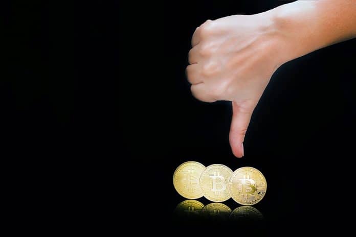 Sinal de negativo na mão com Bitcoin