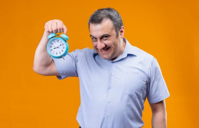 Homem engraçado segurando despertador