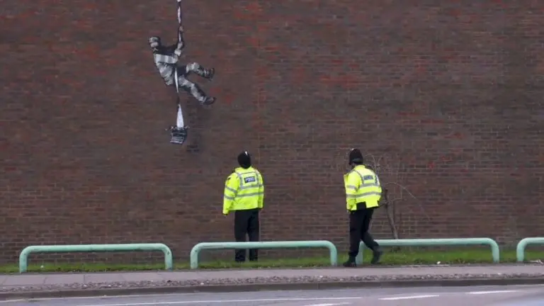 Obra pública do Banksy sendo observada por policiais