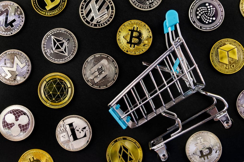 Várias criptomoedas perto de um carrinho de compra alternativas Ethereum Bitcoin Dogecoin Litecoin Monero