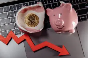 Bitcoin dentro de porquinho quebrado e seta apontando para queda