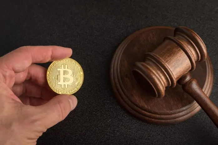 Mão segurando Bitcoin e martelo da justiça