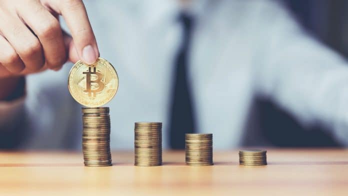 Mão segurando Bitcoin em pilha de moedas