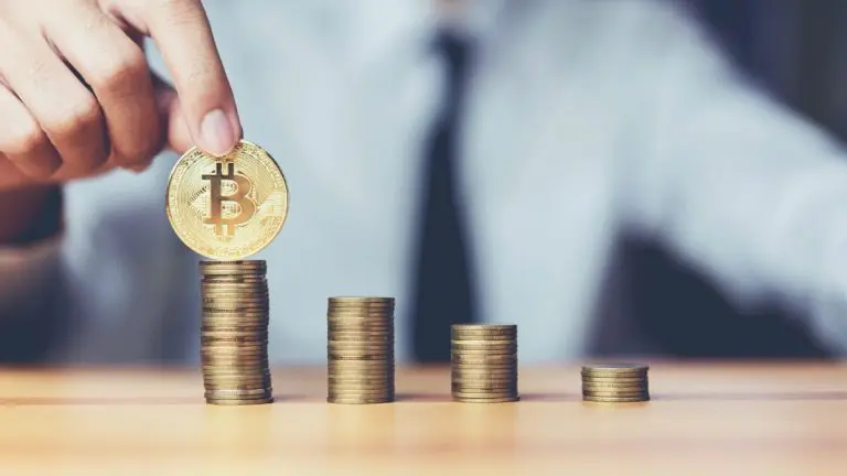 Mão segurando Bitcoin em pilha de moedas