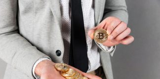 Mão segurando pilha de Bitcoins e outra segurando um Bitcoin
