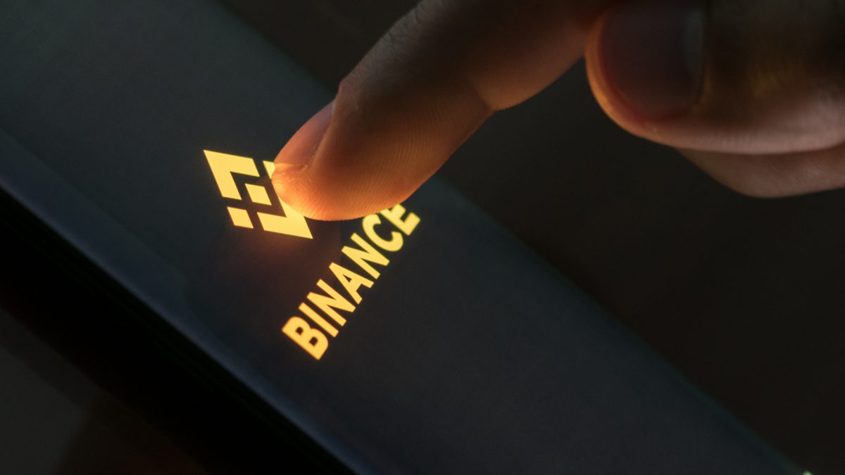 Dedo encostando em aplicativo da Binance, corretora de criptomoedas saques e depósitos