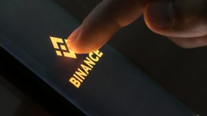 Dedo encostando em aplicativo da Binance, corretora de criptomoedas saques e depósitos