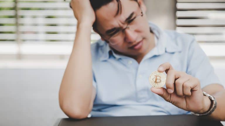 Homem segurando Bitcoin com tristeza