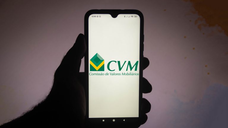 Celular com imagem da CVM Comissão de Valores Mobiliários do Brasil processo processa contra criptomoedas e bitcoin e blockchain