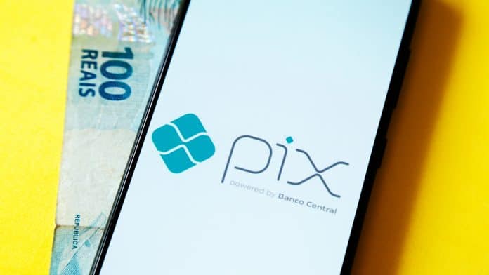 Celular com tela do PIX e nota de R$ 100 do Real brasileiro