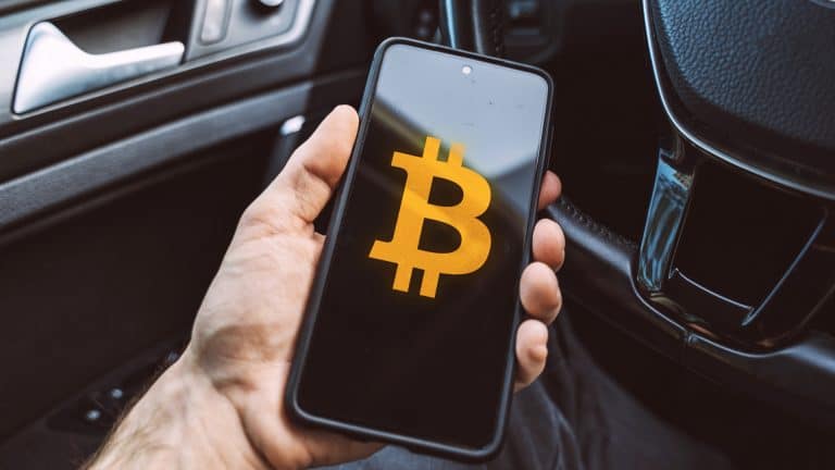Aplicativo de Bitcoin é segurado por pessoa sentada em um carro estacionamento