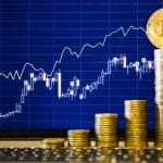 Bitcoin no topo de pilha de moedas e gráfico atrás de alta nos preços