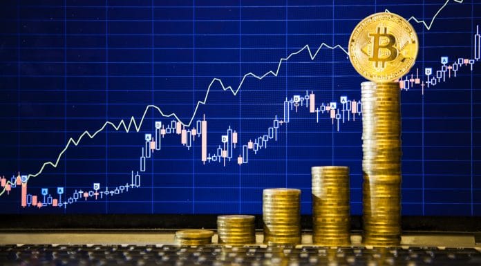 Bitcoin no topo de pilha de moedas e gráfico atrás de alta nos preços