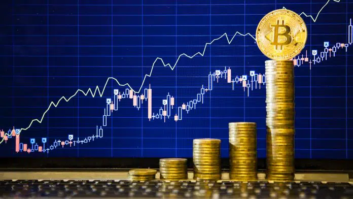 Bitcoin no topo de pilha de moedas e gráfico atrás de alta nos preços