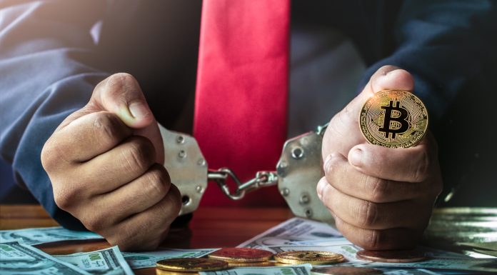 Homem com algemas segurando Bitcoin criptomoedas sequestro prisão