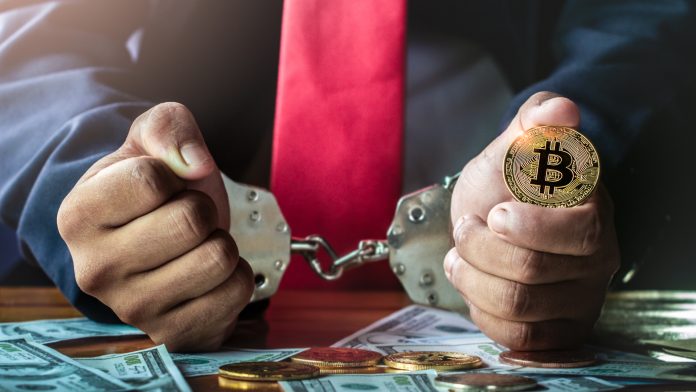 Homem com algemas segurando Bitcoin criptomoedas sequestro prisão