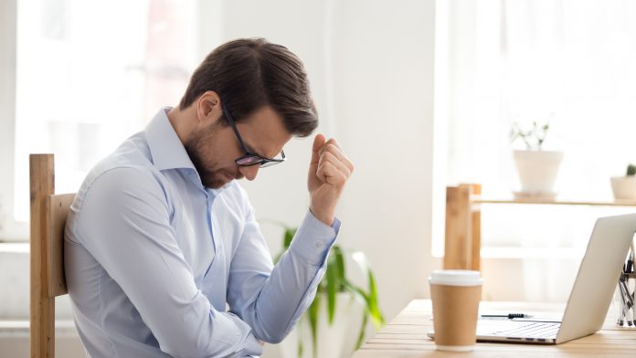 Homem deprimido e frustrado, sentindo-se um perdedor sentado perto do laptop trader