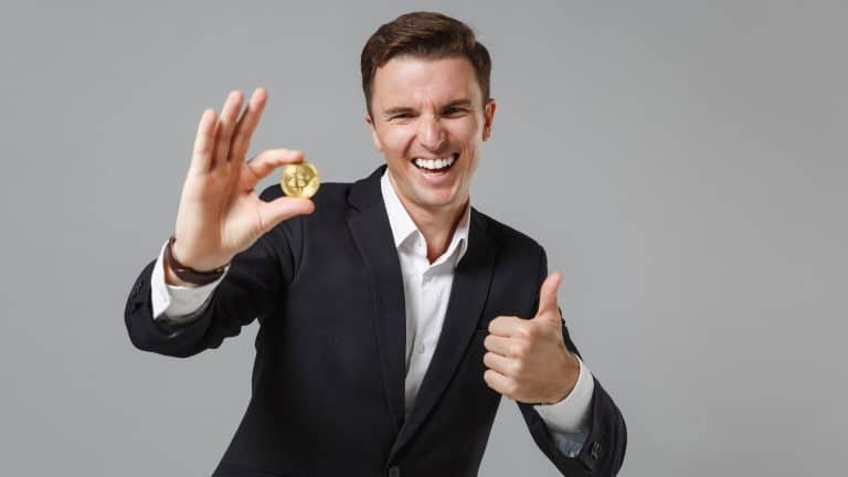 Homem segurando o Bitcoin e rindo