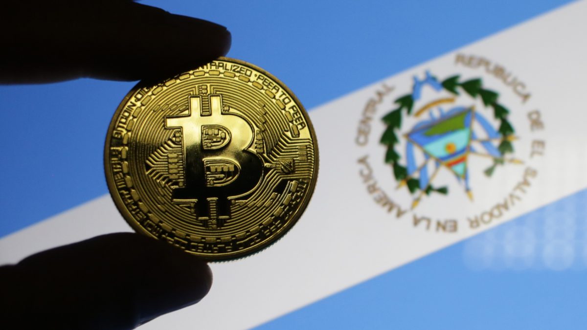 Mão segurando Bitcoin com bandeira de El Salvador