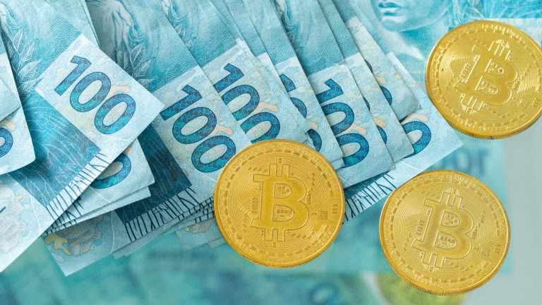 Notas de 100 reais e moedas de Bitcoin Brasil brasileiros
