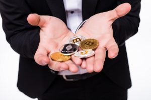 Homem segurando criptomoedas em mão