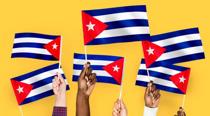 Mãos em Cuba segurando bandeiras com fundo laranja Bitcoin