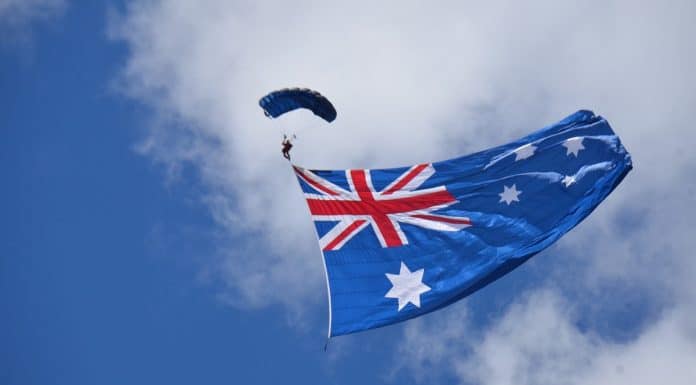 Pessoa de paraquedas próximo a bandeira da Austrália