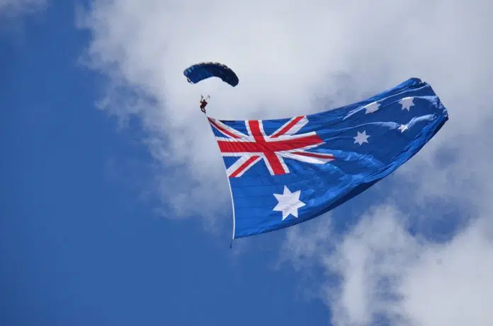 Pessoa de paraquedas próximo a bandeira da Austrália