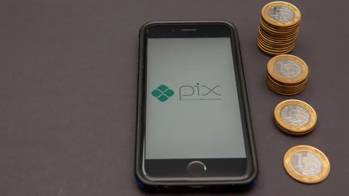 Vista de celular com logo do PIX e pilha decrescente de moedas limite de transações