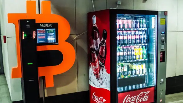 Caixa eletrônico de Bitcoin ao lado de máquina de Coca-Cola