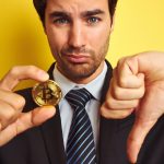 Homem desanimado com Bitcoin e apontando dedo para baixo