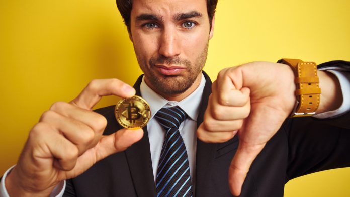 Homem desanimado com Bitcoin e apontando dedo para baixo