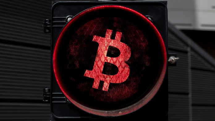 Sinal vermelho com imagem do Bitcoin