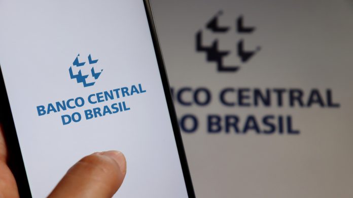 Aplicativo do Banco Central do Brasil em frente a logo da autarquia