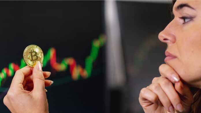 Jovem universitária segurando uma moeda de Bitcoin em estudo