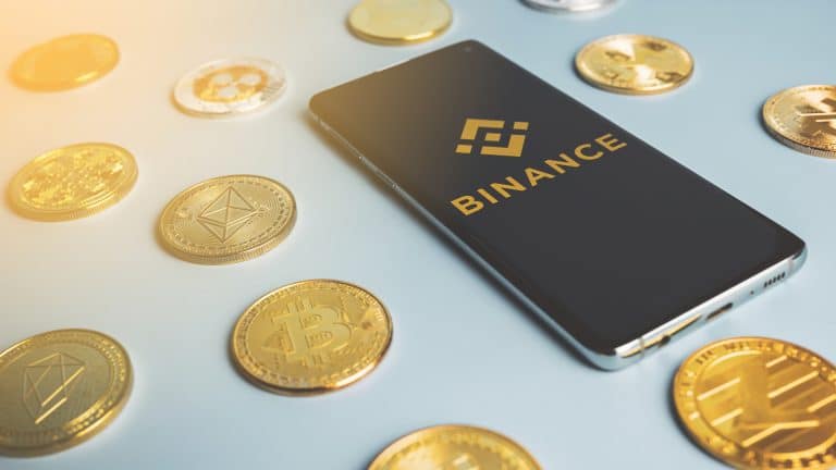 Celular com aplicativo da Binance próximo do Bitcoin e altcoins criptomoedas