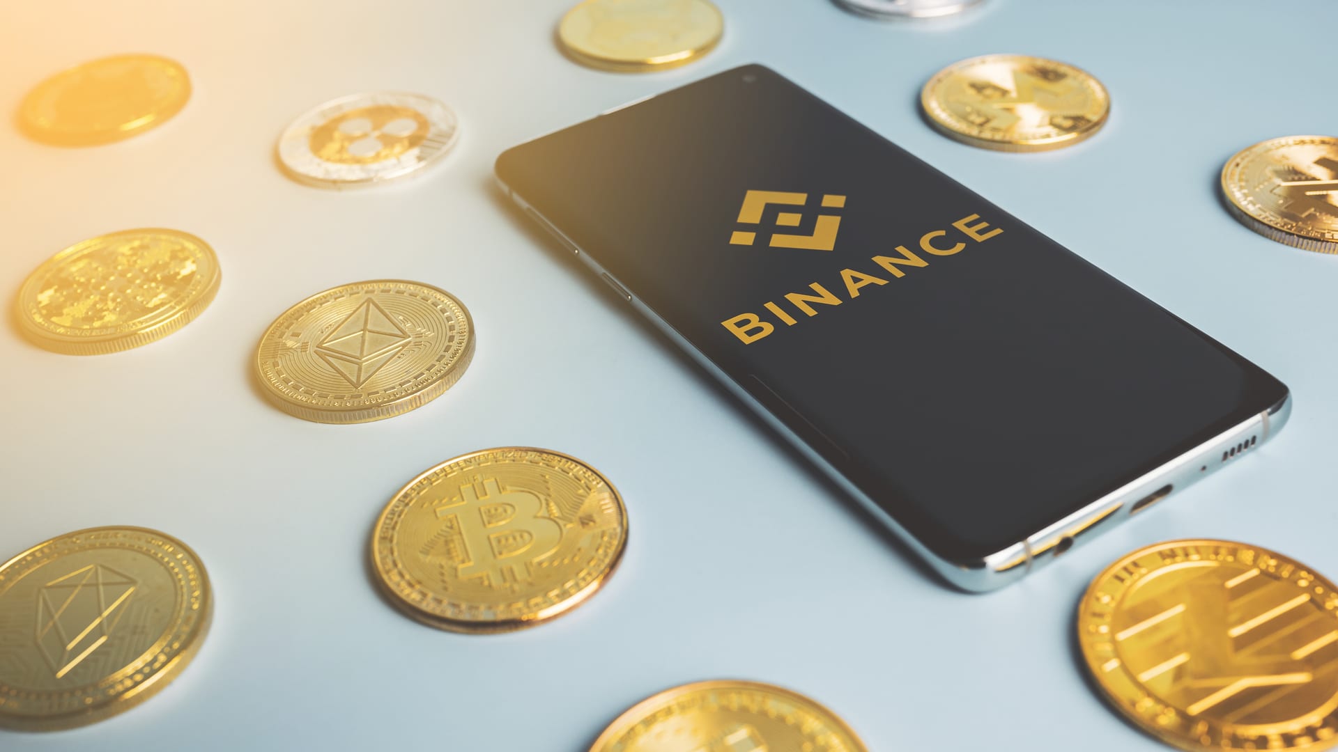 Celular com aplicativo da Binance próximo do Bitcoin e altcoins criptomoedas