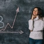 Garota assistindo o gráfico do bitcoin desenhado na lousa com giz