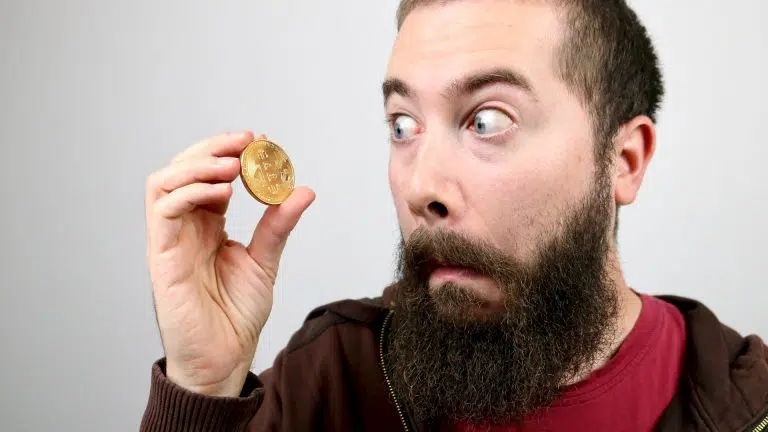 Homem jovem com barba olhando para o Bitcoin