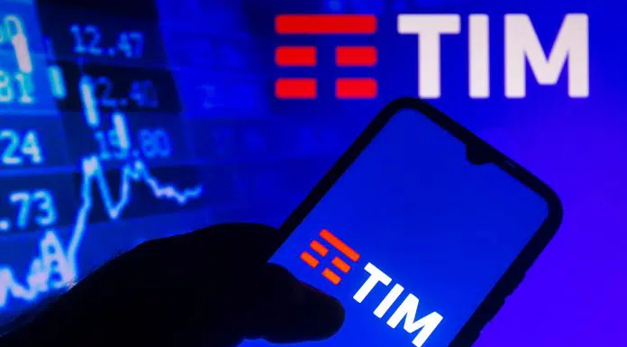Logo da TIM exibido em um smartphone com as informações do mercado de ações em segundo plano
