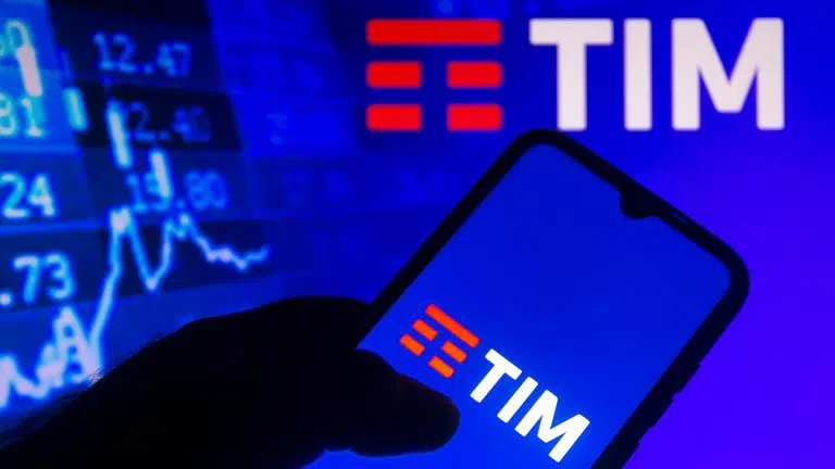 Logo da TIM exibido em um smartphone com as informações do mercado de ações em segundo plano