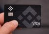Mão segura o cartão de débito Binance, bandeira Visa
