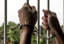 Mãos algemadas de prisioneiro masculino na cadeia