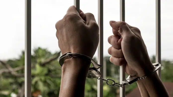 Mãos algemadas de prisioneiro masculino na cadeia