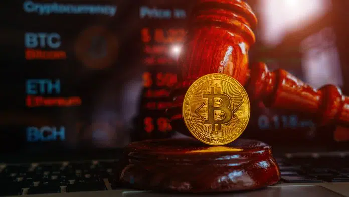 Martelo da Justiça próximo a Bitcoin e gráficos de criptomoedas ao fundo