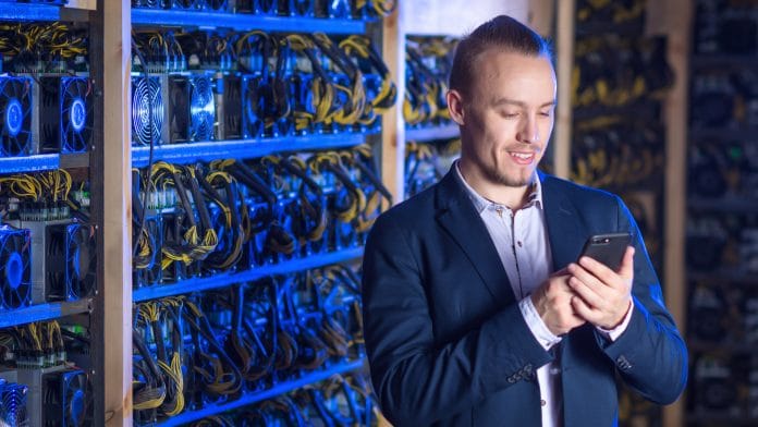 Minerador de Bitcoin rindo próximo a máquinas