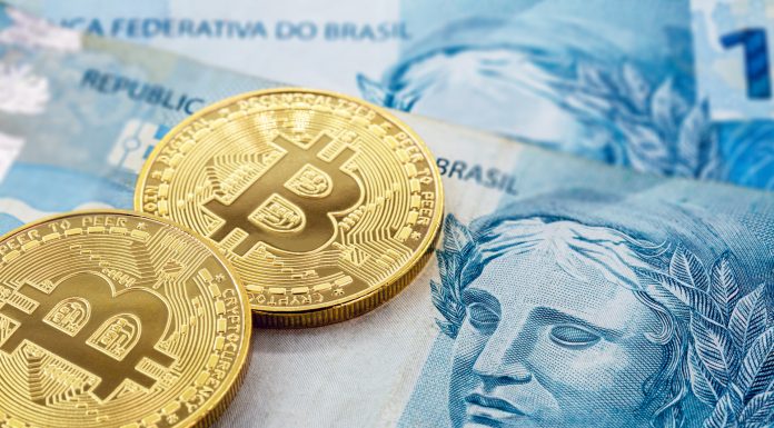 Notas de R$ 100 do Real brasileiro e moedas de Bitcoin