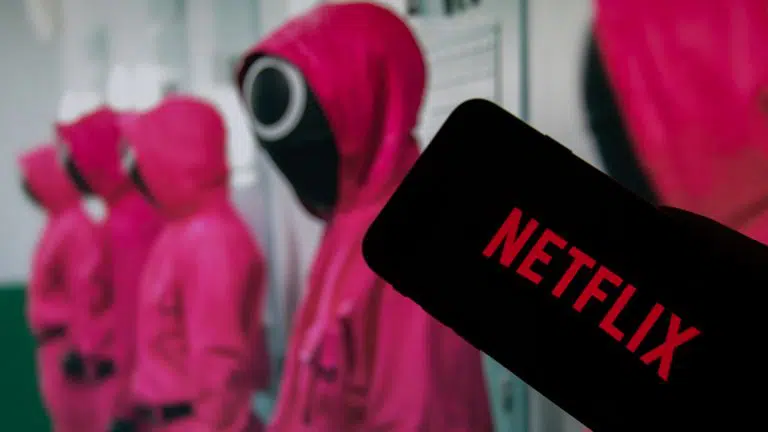 O logotipo da Netflix na tela de um smartphone na frente de uma televisão com a série Squid Game
